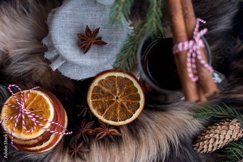 mulled wine set, dry orange slices. Cold winter in the village, Cherry jam on the background of a burning lantern and natural fox fur. photo