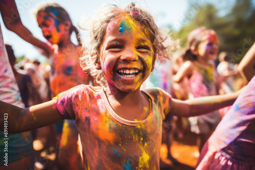 Close-up portrait of happy child with colorful powder on her face and clothes.