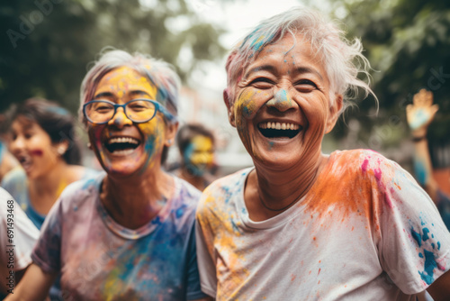 Portrait of happy senior women with their faces and clothes in colorful powder having fun in park.