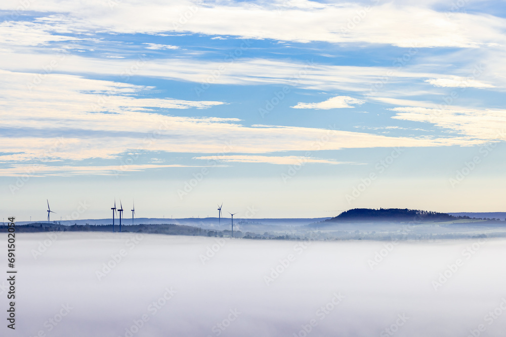 Group with wind turbines in a rolling misty landscape view