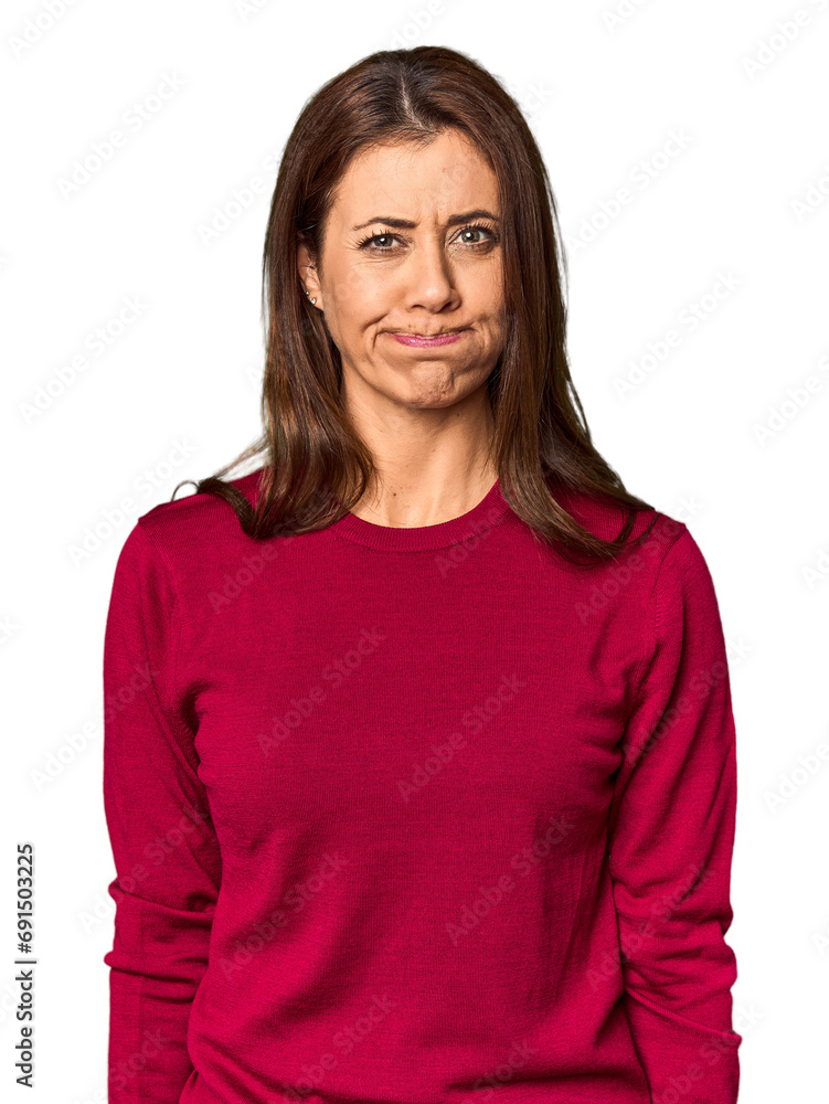 Fototapeta premium Elegant middle-aged Caucasian woman in studio setting blows cheeks, has tired expression. Facial expression concept.