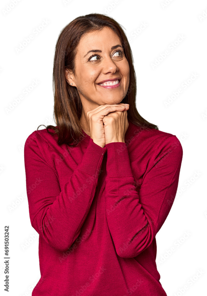 Elegant middle-aged Caucasian woman in studio setting keeps hands under chin, is looking happily aside. Elegant middle-aged Caucasian woman in studio setting keeps hands under chin, is looking happily aside.