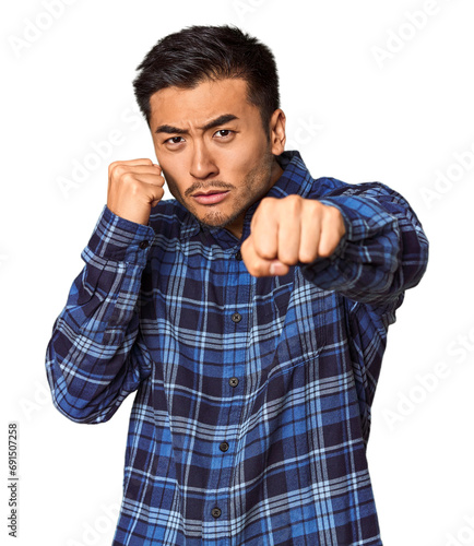 Young Chinese man in studio background throwing a punch, anger, fighting due to an argument, boxing.