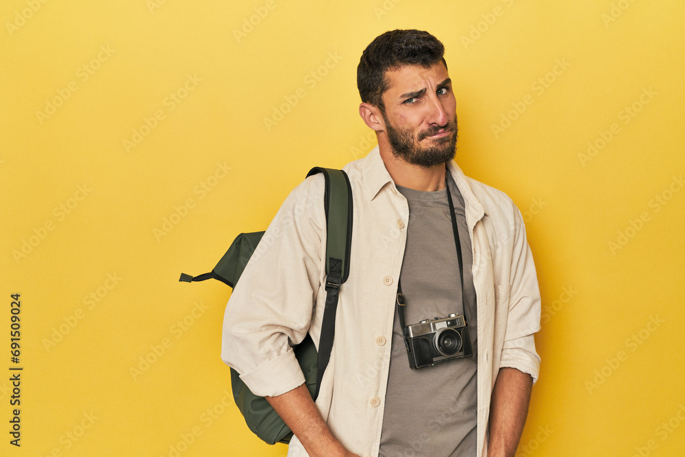 Fototapeta premium Young Hispanic travel photographer poses confused, feels doubtful and unsure.