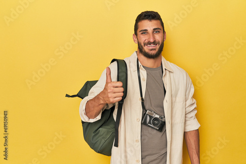 Young Hispanic travel photographer poses smiling and raising thumb up photo