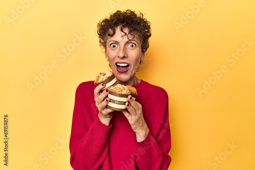 Eager woman reaching for muffins on a vibrant yellow studio background
