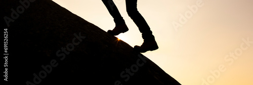 Beine mit Bergstiefeln auf einem Berggipfel im Gegenlicht