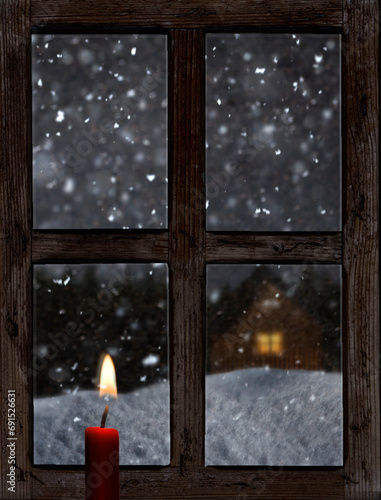 Blick durch ein altes Holzfenster mit Kerze im Winter