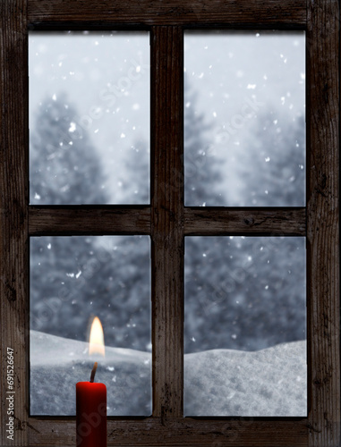 Blick durch ein altes Holzfenster mit Kerze im Winter photo