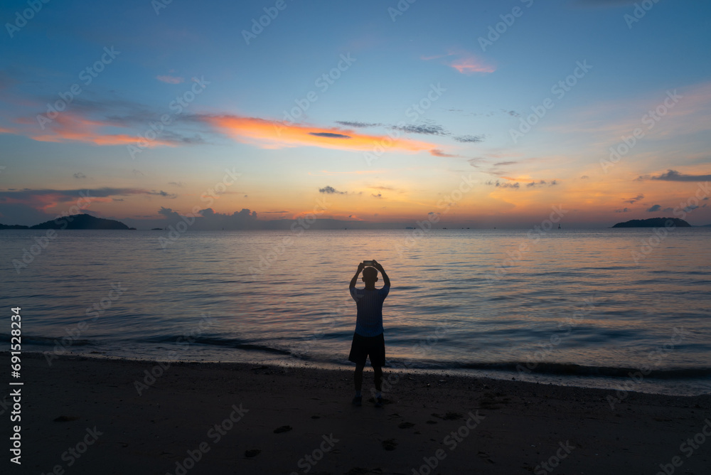 A man taking photo of sunrise in the sea at Phuket city
