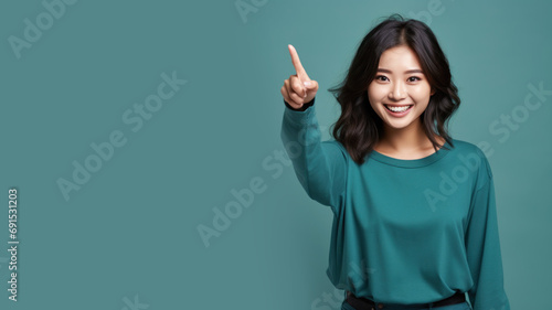 Happy asian woman pointing her finger at copy space for promotion