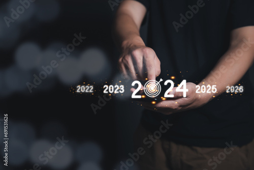 Man Finger pressing on start year 2024 button on smartphone with copy space for text. Concept of new year. Businessman pressing 2024 start up business. Beginning of New Year 2024. photo