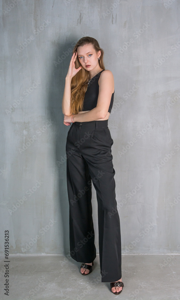 Young beautiful woman, fashion model, in a black suit in the studio