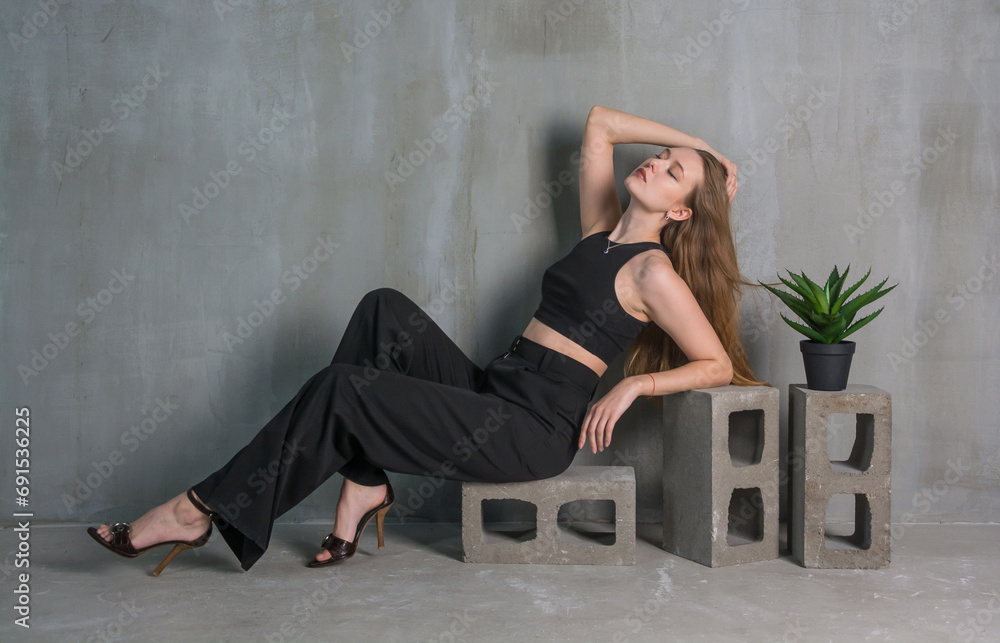 Young beautiful woman, fashion model, in a black suit in the studio