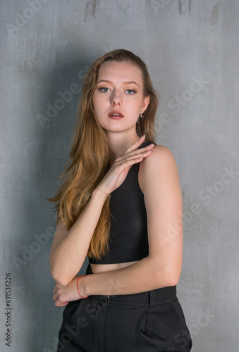 Young beautiful woman, fashion model, in a black suit in the studio