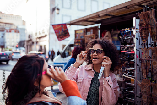 Two female friends trying on sunglasses in the city photo