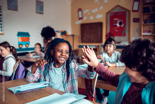 Little boy and girl high fiving in classroom photo