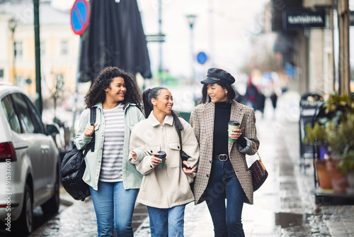 Young women in stylish clothes walking in the city photo