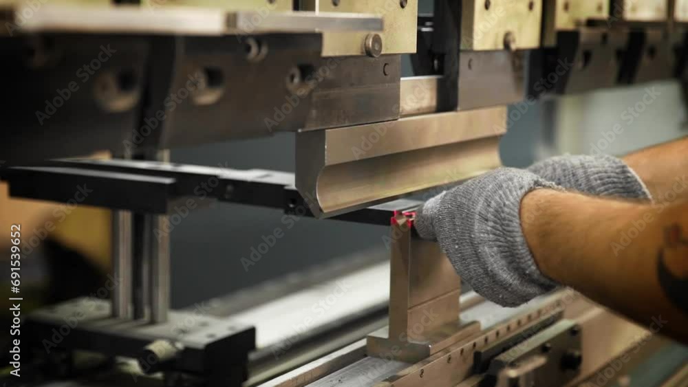 The engineer does the bending of the metal sheet on a hydraulic machine The engineer does the bending of the metal sheet on a hydraulic machine
