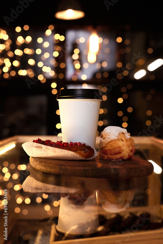 White glass of coffee with eclair on a background of Christmas lights. Mockup. © Лев Малевич