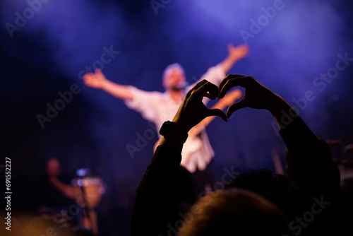 The concert music fan make a heart shape with their hands.