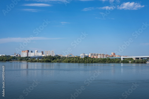 The city by the river on a sunny morning, multi-storey houses in the forest area