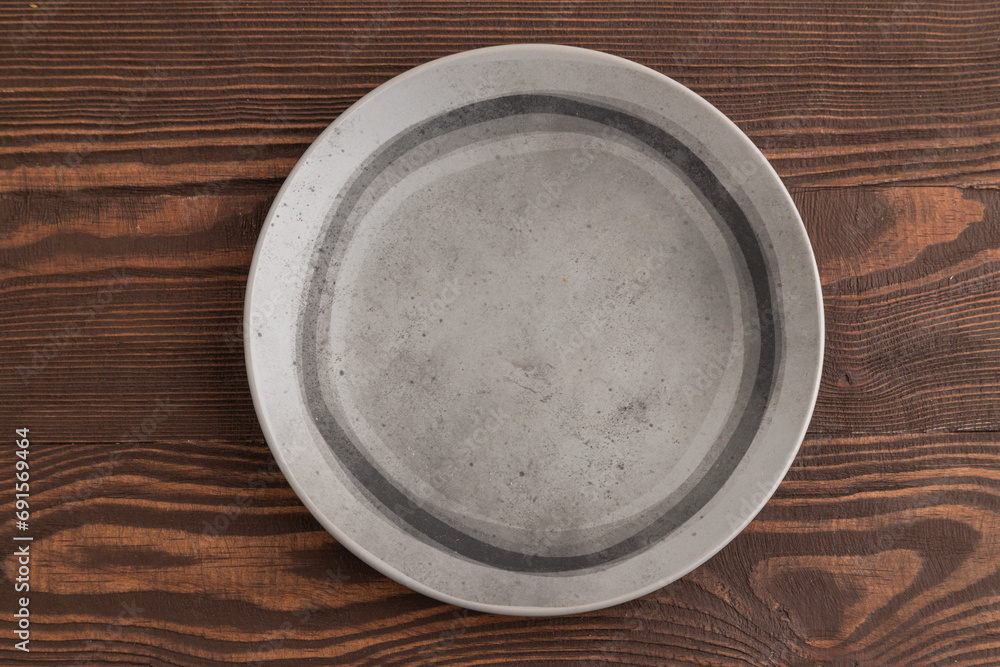 Empty gray ceramic plate on brown wooden background. Top view, copy space Empty gray ceramic plate on brown wooden background. Top view, copy space