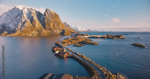 Aerial view of snowy rocks, islands with rorbuer, sea, bridge, mountains, road, sky with clouds at sunrise in winter. Beautiful top drone view of rorbu in Hamnoy village, Lofoten islands, Norway	 photo