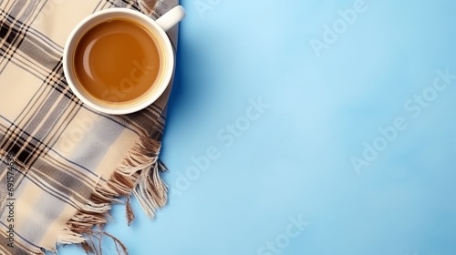 Coffee and warm plaid on a light blue background in a flat lay composition with text space