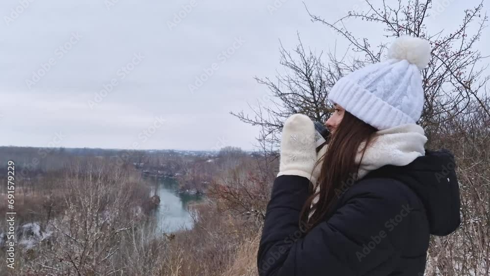 Pretty carefree woman enjoys a day in the winter park while drinking a cup of coffee or hot chocolate, admiring the first snow Pretty carefree woman enjoys a day in the winter park while drinking a cup of coffee or hot chocolate, admiring the first snow