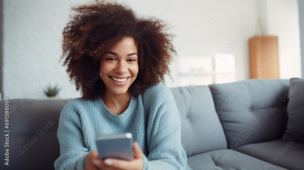 Smiling woman sits on the couch at home and stares into her smartphone Smiling woman sits on the couch at home and stares into her smartphone