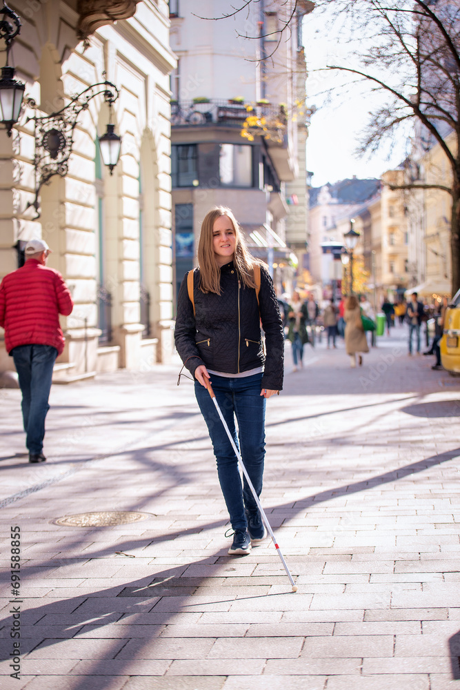 ortrait of blind woman with white cane walking on the street