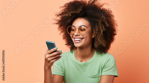 Young girl smiling holding a smartphone sitting against colored background