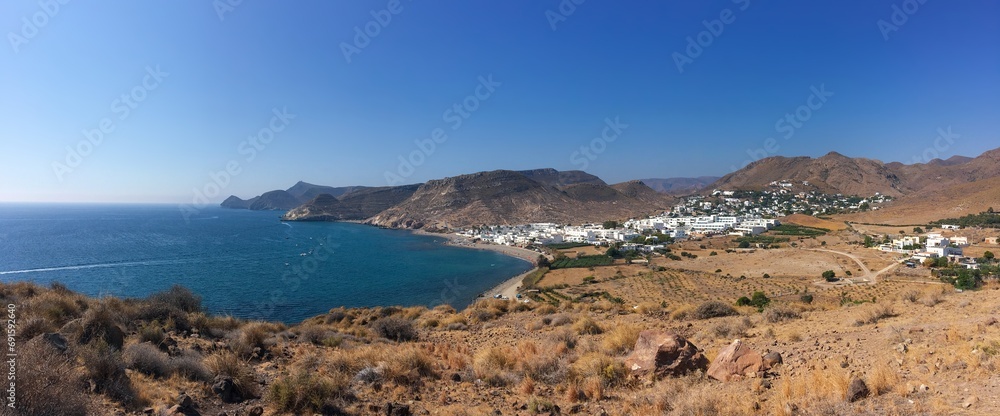 Panorámica del pueblo Las Negras desde la costa norte. Costa rocosa y soleada con un mar de aguas turquesasa junto a Las Negras en el cabo de Gata, Almería, España.