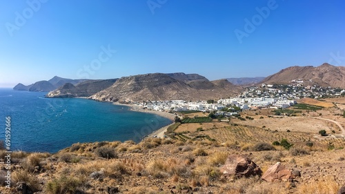 Panorámica del pueblo Las Negras desde la costa norte. Costa rocosa y soleada con un mar de aguas turquesasa junto a Las Negras en el cabo de Gata, Almería, España.