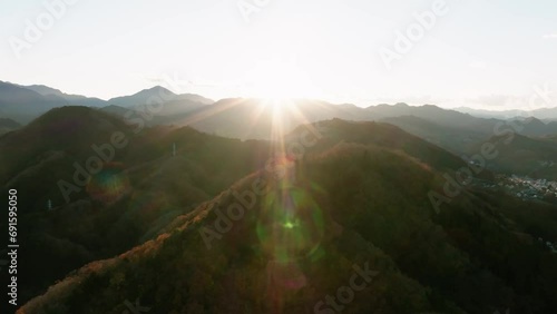 遠くの山に沈む夕日と夕日に照らされた紅葉した山々　空撮 photo