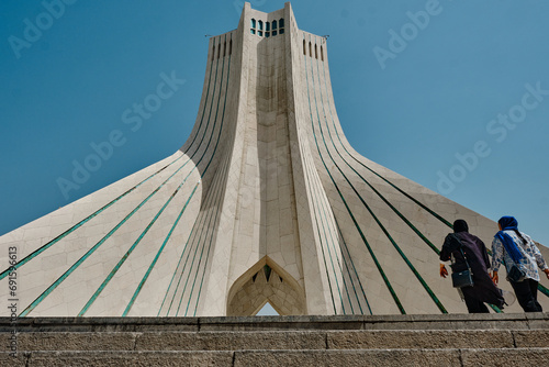 Teheran, Iran, 06.25.2023: Tower in Iran, tower of freedom or liberty low angle view with two local women.