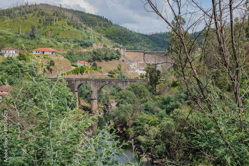 Landscape with arched bridge over the Zêzere river in aerial view among trunks and leaves and Bouçã dam in the background, PORTUGAL photo