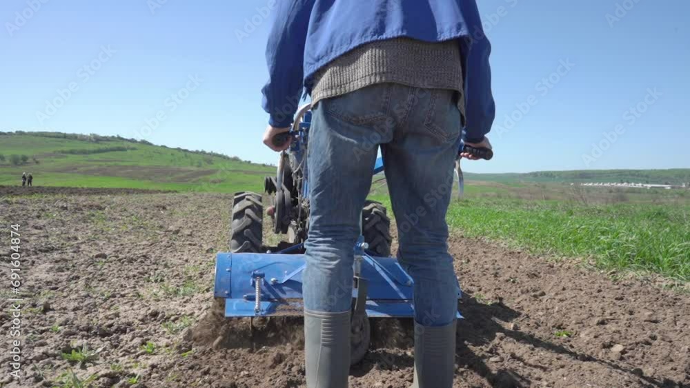cultivation of land in the spring season, a man drives a walk-behind tractor in the field, cultivating the land cultivation of land in the spring season, a man drives a walk-behind tractor in the field, cultivating the land