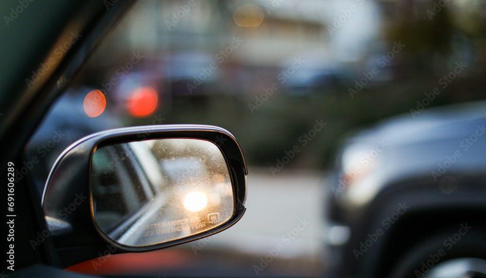 car mirror reflecting cityscape, symbolizing travel, reflection, urban lifestyle, and exploration. Blurred background