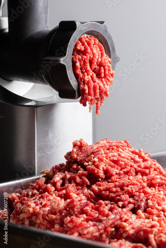 Minced beef meat comes out fo mincing machine close view