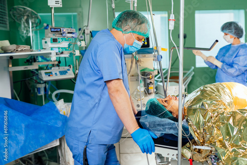Male anesthesiologist talking with female patient after epidural anesthesia in the operating room in the maternity ward of the hospital. photo