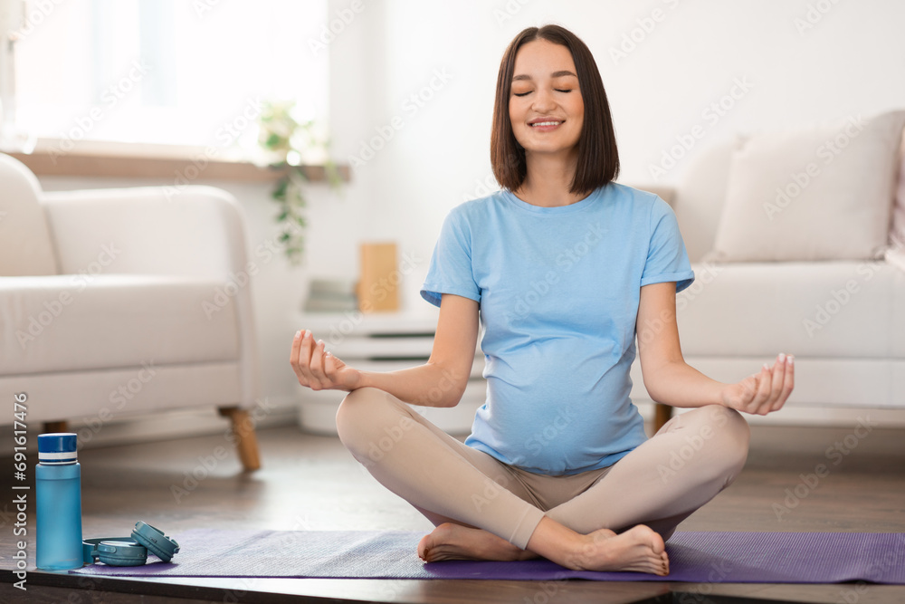 Smiling calm pregnant woman in casual practicing prenatal yoga indoor Smiling calm pregnant woman in casual practicing prenatal yoga indoor