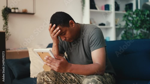 African American soldier looking at family photo, missing wife, homesickness