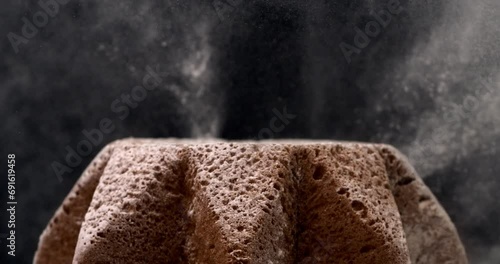 Super slow motion macro of falling white powdered sugar dust particles on Italian culture christmas holidays artisan homemade baked Pandoro cake isolated on black background at 1000 fps. photo