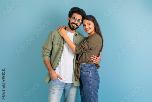Beautiful millennial indian couple posing on blue studio background