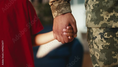 Little boy holds soldier father's hand, parent leaving for the military service photo
