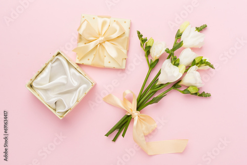 Open gift box, with fresia flower color background, top view © Liami