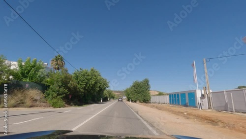 First person view, FPV, from dashcam of car driving along the Algarve Coast in Portugal, driving on the highway towards Faro. Road trip video in POV, with blue sky