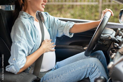 Cropped of pregnant lady driver navigating car vehicle touching belly © Prostock-studio
